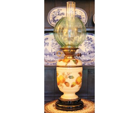 A late 19th century ceramic oil lamp, pale green shade with a vase shaped body decorated with fruit blossom, 60cm