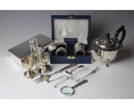 A cased set of four white metal napkin rings, decorated with flowers and scrolls, a commemorative silver spoon, a silver hand