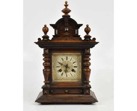 An early 20th century German mantel clock with carved finials above the dial set with floral details and Roman numerals, with