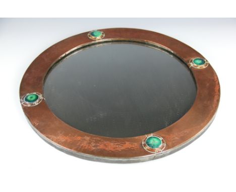 A Liberty & Co copper circular wall mirror, set with four Ruskin style cabochons, (two cabochons damaged), 56cm diameter
