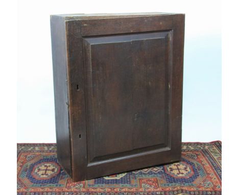 A George III oak wall cabinet, with panelled door enclosing a shelf and eight pigeon holes, 92cm H x 72cm W x 32cm D