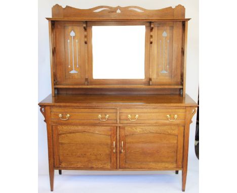 An Arts and Crafts light oak dresser, in the manner of Liberty and Co, with mirror back with pierced foliate detailing, above