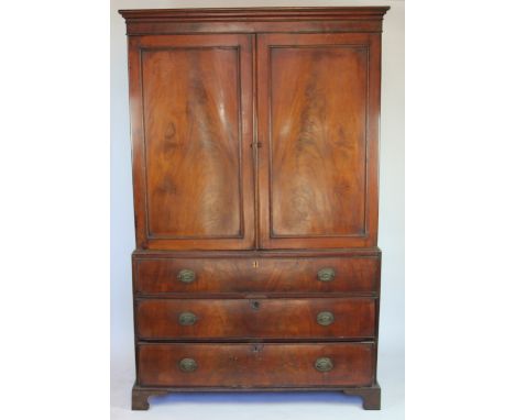 A George III mahogany linen press, with two doors enclosing five press trays, over two short and two long drawers, on bracket