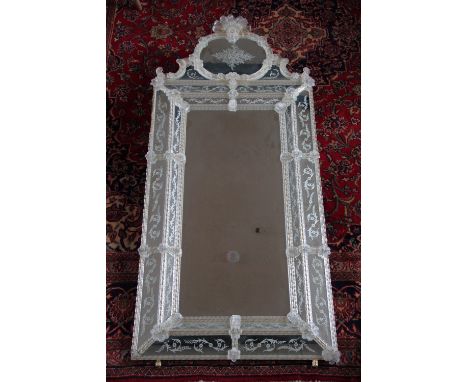 A large Venetian glass wall mirror, with shell shaped crest and oval panel over a rectangular plate within a foliate and spir