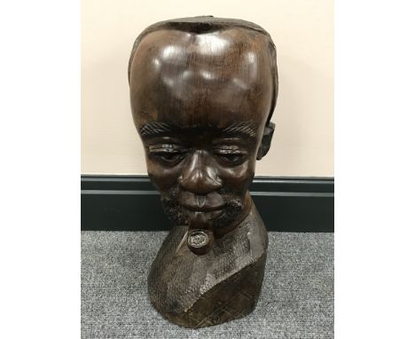 A carved hardwood head of an African man smoking a pipe