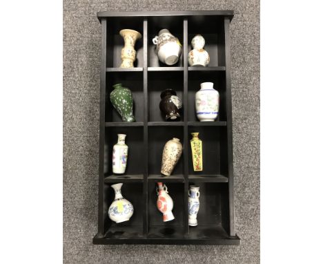 A small shelf containing twelve miniature Chinese vases 