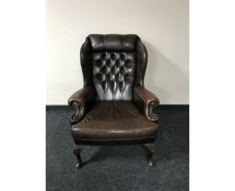 A brown button Chesterfield wing back armchair 
