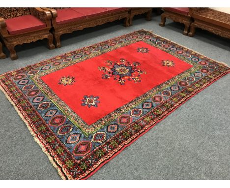 A woollen fringed eastern carpet of geometric design on red ground