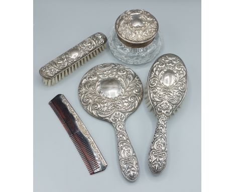 A Birmingham silver five piece dressing table set comprising two brushes, a hand mirror, a comb and a dressing table bottle 