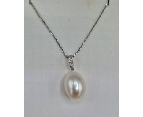 An 18ct white gold pearl and diamond pendant set with three diamonds above a large pear shaped pearl and with 18ct gold chain