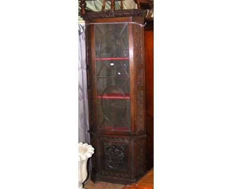 An antique carved oak corner display cabinet