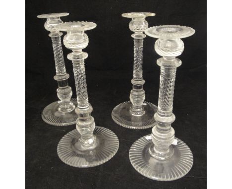 A set of four near matching 18th or early 19th Century cut glass candlesticks with wrythen cut and ringed columns raised on c