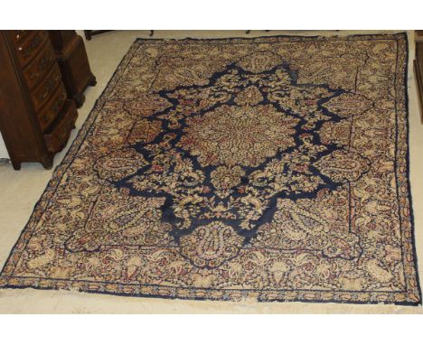 A Chinese carpet, the central floral decorated medallion in cream, green, salmon and pale red on a dark blue ground scrolling