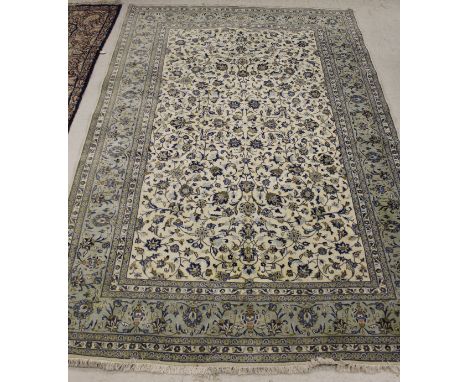 A Persian style carpet, the central panel set with all-over floral decoration on a cream ground within a green, blue and crea