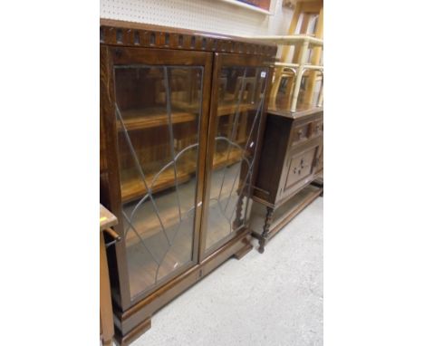 An oak bookcase with leaded and glazed doors enclosing four shelves, raised on bracket feet, together with an early 20th Cent