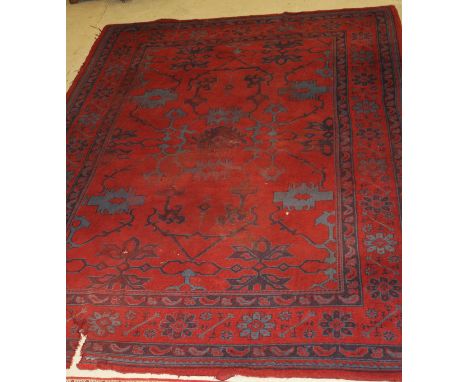 A Donegal carpet, the central panel set with scrolling decoration on a red ground, within a stepped red and blue stylised flo