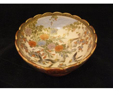 A Japanese Meiji Period Satsuma bowl with shaped rim, the centre field decorated with birds in flight over flowers by water's