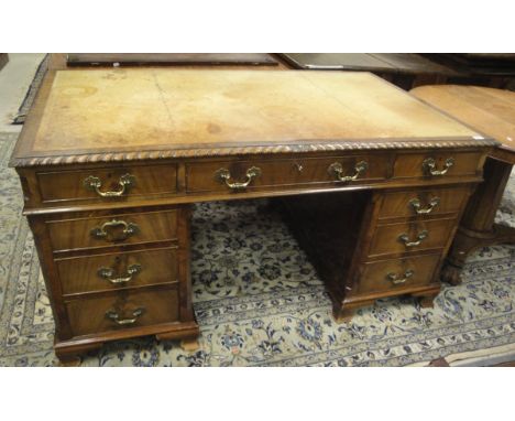 A 20th Century mahogany desk in the Georgian style, the top with tooled and gilded leather insert with a gadrooned and acanth