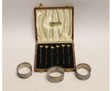 A cased set of six sterling and enamel cocktail sticks, with cockerel terminals and three silver napkin rings.