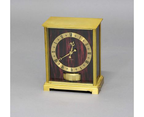JAEGER LE COULTRE EMBASSY ATMOS CLOCK, the brass chapter ring on a red marbled ground and side panels, above a balance wheel,