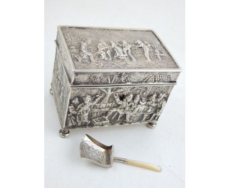 A 19th century Dutch white metal tea caddy, embossed with figures in townscape, purity marks to base, together with an Englis