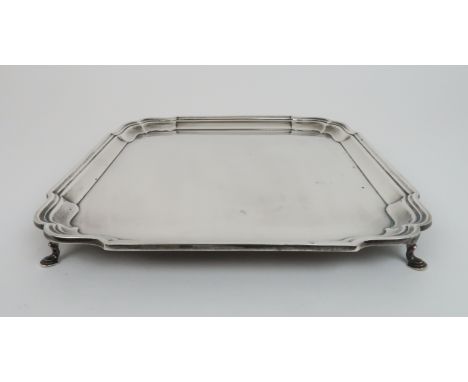 A SILVER SALVER by R &amp; W Sorley, Chester 1936 of square form with scalloped corners &amp; stepped rim on four pad feet 30
