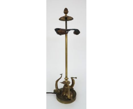 A GILDED METAL TABLE LAMP the reeded column pineapple finial and three bulb holders, the base with three dolphins, 55cm high 