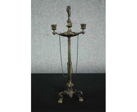 A nineteenth century brass candlestick. With three arms of candle holders bound by chains. With three ornate legs and mounted