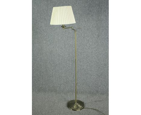 A modern standing floor lamp with articulated adjustable arm. Metal with a brass effect finish. H.150cm.