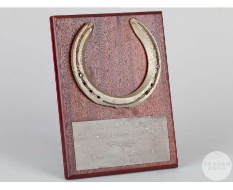 Shoe worn by the racehorse Iktamal, mounted on a wooden plaque with easel support&nbsp;and set with an engraved metal plaque,