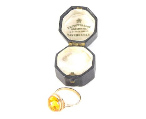 A 9ct gold dress ring, set with oval piece of amber, pierced and textured shank. (cased) 