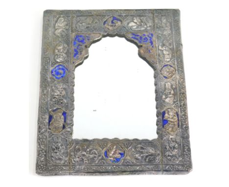 An Indian mirror, with shaped glass, profusely repousse decorated with panels and figures, inset with blue enamel, white meta