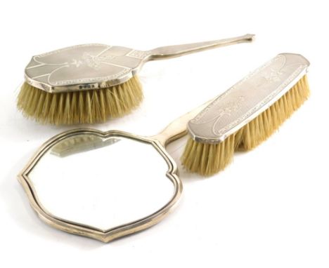 A George V silver part dressing table set, comprising hairbrush, clothes brush and hand mirror, 25cm high, partially chased a