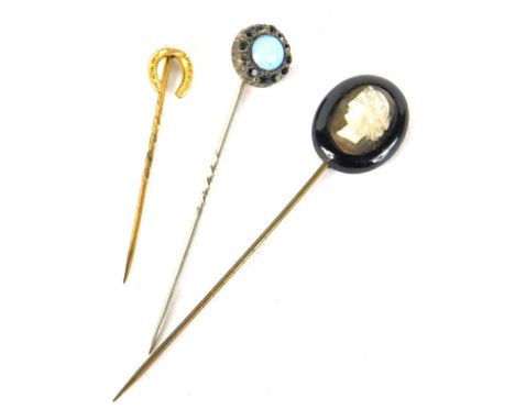 An early 20thC stick pin, with partial turned stem and horseshoe top, 4cm high, another with cameo, and a further stick pin. 