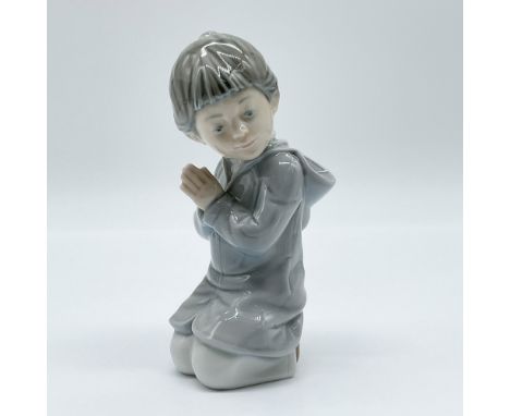 This delicate Nao by Lladro porcelain figurine, titled Guide Me, captures a young girl in a moment of serene contemplation, h