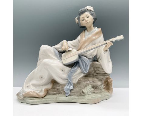 Nao by Lladro porcelain figurine depicting a graceful geisha seated on a rock while playing a shamisen. This finely detailed 