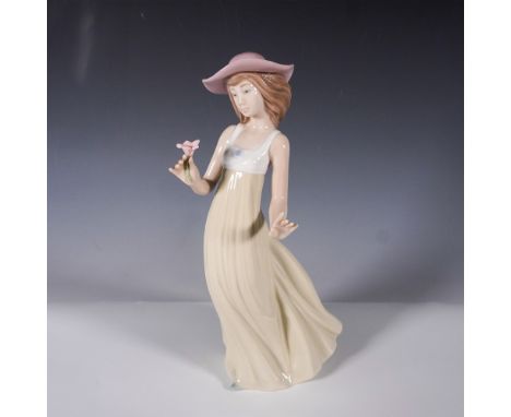 Nao by Lladro porcelain figurine depicting a young woman in a flowing cream-colored gown, delicately holding a pink flower in