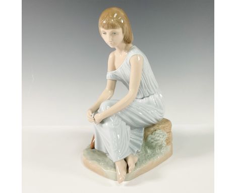 Charming figurine featuring a young girl seated on a stone wall, deep in thought. The figurine showcases a serene expression 