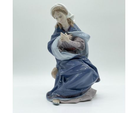 The figurine depicts the Virgin Mary in a serene seated pose, adorned with a flowing blue mantle and delicate white veil. The