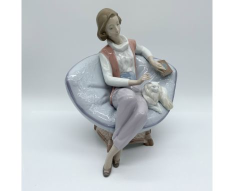 This Lladro figurine, A Quiet Evening (#6638), depicts a woman lounging in a plush chair, gently petting her cat while holdin