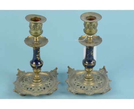 A pair of Edwardian brass candlesticks on pierced square bases and blue enamel stems with gilt spider web decoration