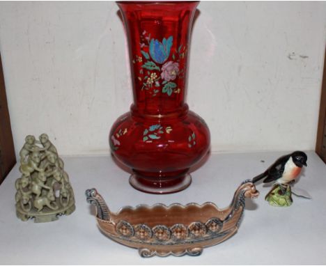 A cranberry glass vase with floral decoration, a Beswick figure of a 'Stonechat', a Wade pottery Viking boat and a carved soa