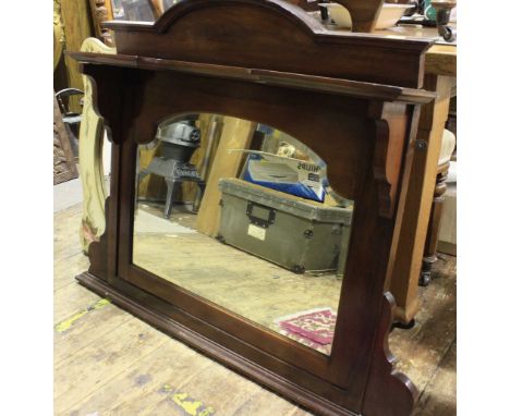 An Edwardian stained walnut overmantel mirror, with arched pediment, raised shelf above a shaped bevelled glass.