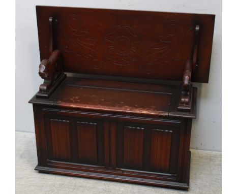 An oak 20th Century monk’s bench with hinged back, the box seat with carved and panelled front on plinth base, 106cm.