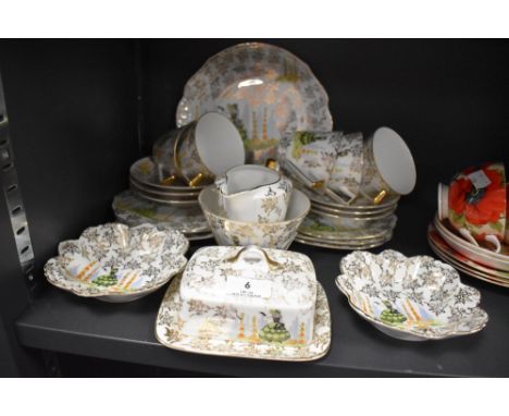 A vintage part tea set having gilt floral pattern, and garden scene depicting a crinoline lady with basket in green, blue and