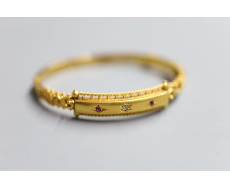 An Edwardian 15ct gold and gypsy set ruby and diamond three stone hinged bangle, gross 11.1 grams (a.f.).CONDITION: Two repai