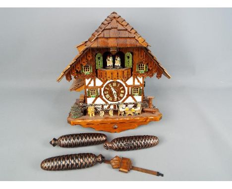 A black forest cuckoo clock with three weights and pendulum.