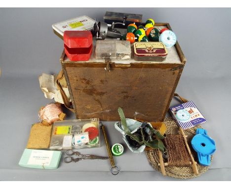 A wooden fishing box containing a good selection of hooks, weights, line, floats, spinners, reels, tools, scales, keep net an