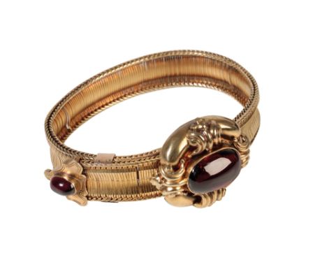 A VICTORIAN GARNET BRACELET set on unmarked yellow metal, the oval-cut cabochon garnet, set to the centre of a scroll work mo