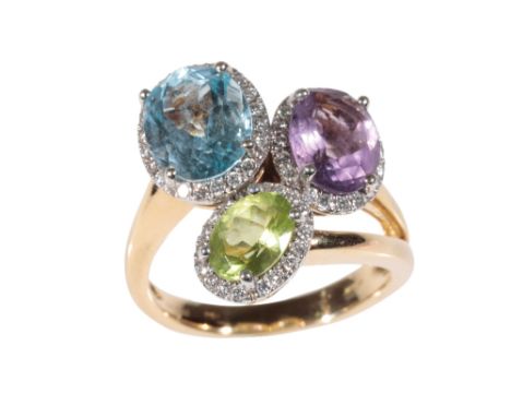 A TRIPLE-GEM SET DRESS RING three oval mix cut gemstones, 'peridot'; 'blue topaz' and 'amethyst, claw set within a border of 